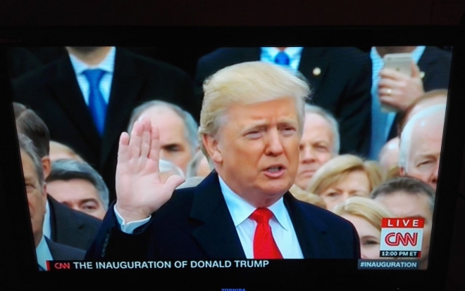 ▲親の代からの聖書の上に手を置き宣誓式に臨むトランプ新大統領(2017年1月20日、CNN放送の中継から)