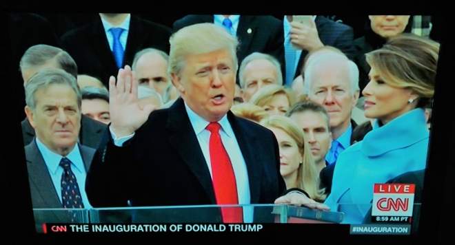 ▲親の代からの聖書の上に手を置き宣誓式に臨むトランプ新大統領（2017年1月20日、CNN放送の中継から）